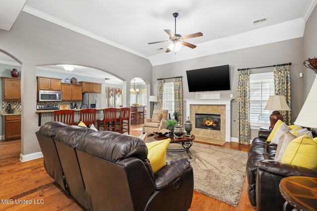 living room with arched walkways, visible vents, and light wood-style floors