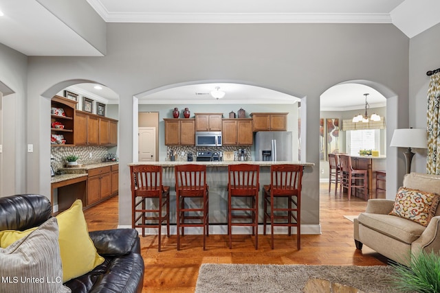 kitchen featuring brown cabinetry, open floor plan, and appliances with stainless steel finishes