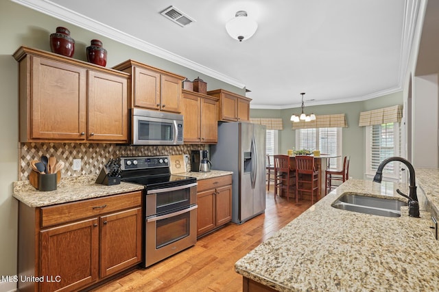 kitchen with visible vents, light wood-style flooring, a sink, tasteful backsplash, and appliances with stainless steel finishes