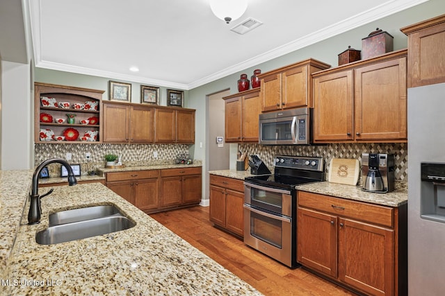 kitchen featuring wood finished floors, a sink, decorative backsplash, ornamental molding, and stainless steel appliances