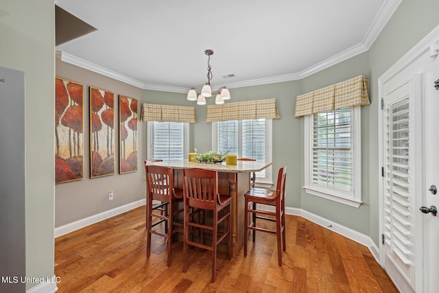 dining area featuring hardwood / wood-style floors, crown molding, and a healthy amount of sunlight