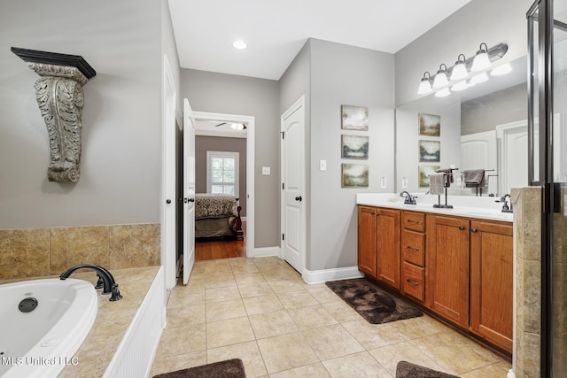 bathroom featuring a garden tub, ensuite bathroom, tile patterned flooring, double vanity, and baseboards