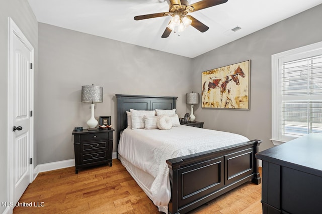 bedroom with light wood-type flooring, visible vents, baseboards, and a ceiling fan