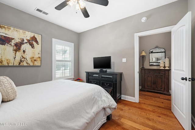 bedroom featuring visible vents, light wood-style flooring, a ceiling fan, and baseboards