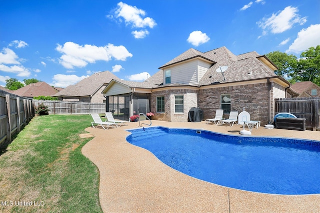 view of swimming pool featuring a sunroom, a lawn, a fenced backyard, and a patio area