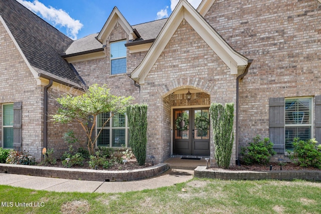 entrance to property with french doors, brick siding, and a shingled roof