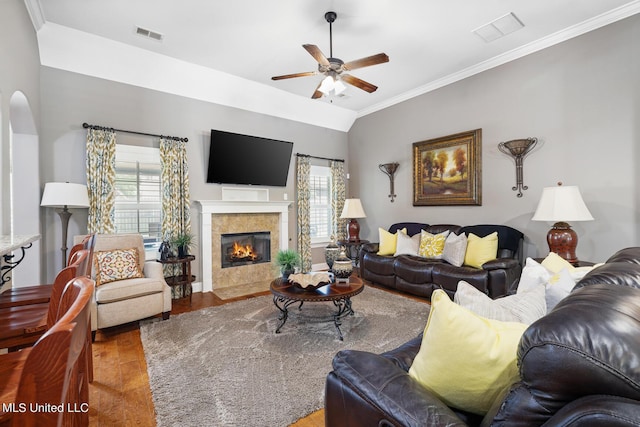 living room with visible vents, crown molding, and a tile fireplace