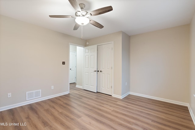 unfurnished bedroom featuring ceiling fan, a closet, and light wood-type flooring