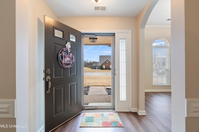 foyer entrance with crown molding and dark hardwood / wood-style floors