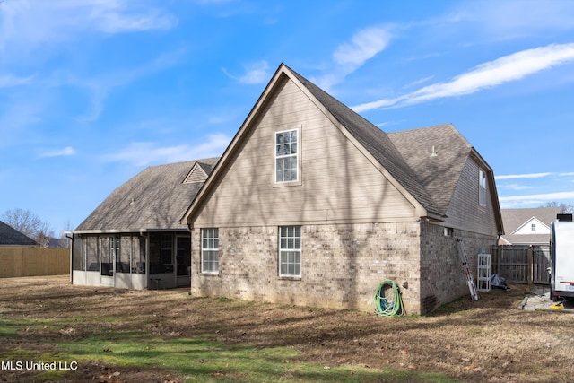 rear view of property featuring a lawn and a sunroom