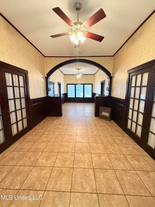 interior space with light tile patterned flooring, ceiling fan, a textured ceiling, and ornamental molding