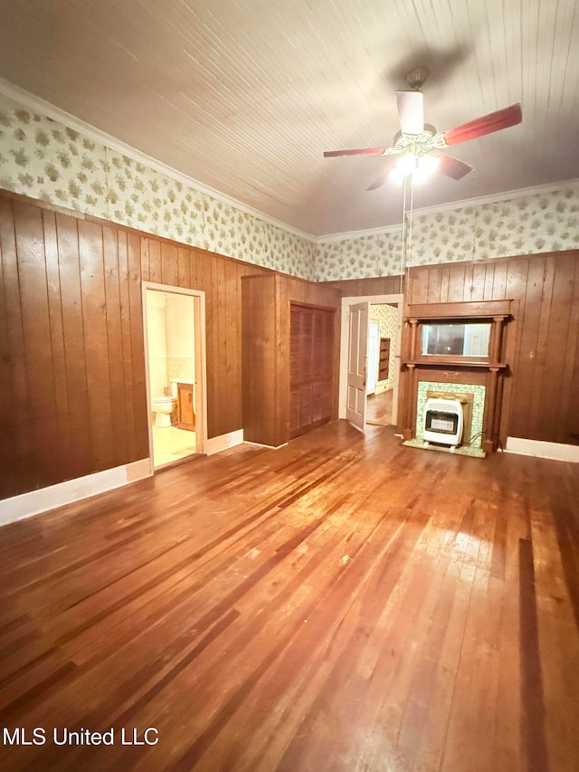 unfurnished living room with wood walls, heating unit, hardwood / wood-style flooring, and ceiling fan