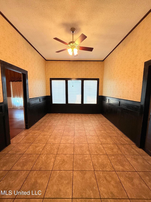 tiled empty room featuring a textured ceiling, ceiling fan, and crown molding