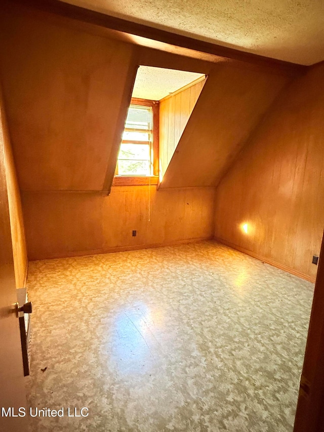 bonus room featuring wood walls, a textured ceiling, and vaulted ceiling