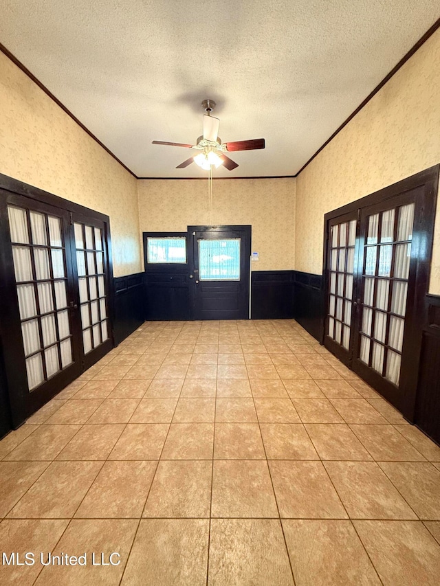 interior space featuring french doors, a textured ceiling, light tile patterned floors, ceiling fan, and crown molding