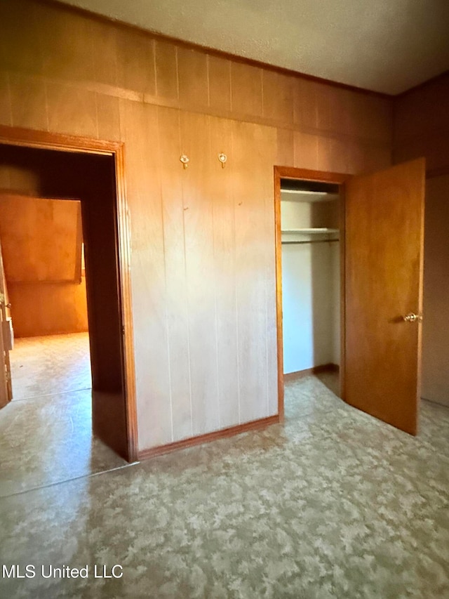 unfurnished bedroom featuring wooden walls and a closet