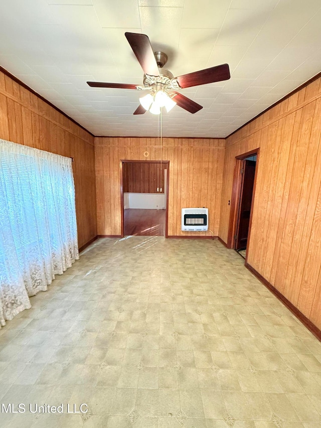 unfurnished living room featuring wood walls, ceiling fan, and heating unit