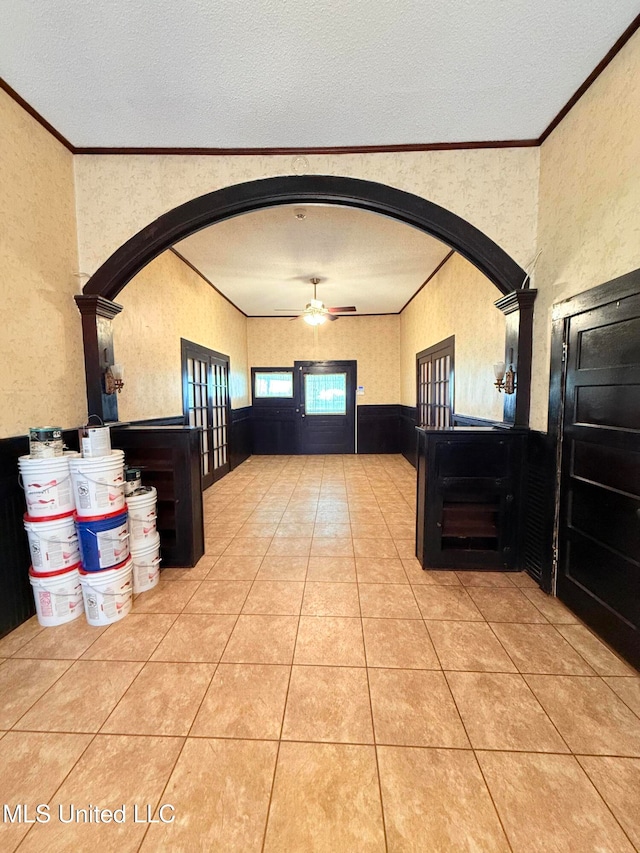 tiled foyer with ornamental molding, a textured ceiling, ceiling fan, and decorative columns