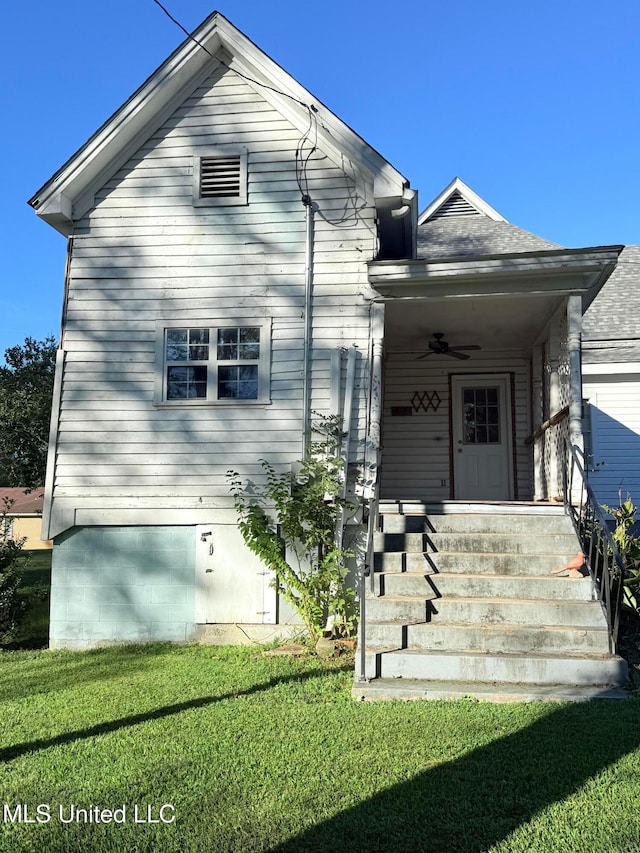 view of front of property with ceiling fan and a front yard