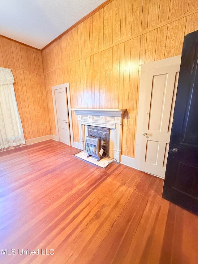 unfurnished living room with wooden walls, hardwood / wood-style floors, and a wood stove