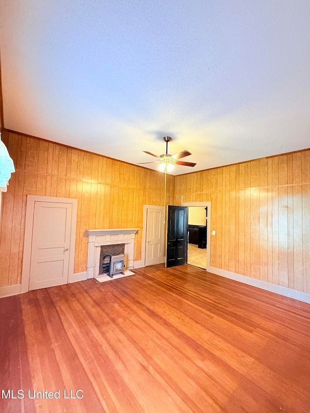 unfurnished living room featuring light wood-type flooring, wooden walls, and ceiling fan