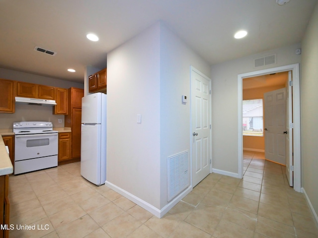 kitchen featuring under cabinet range hood, white appliances, visible vents, light countertops, and brown cabinetry