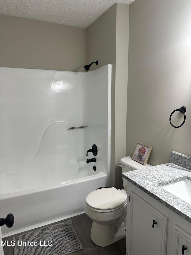 full bath with shower / washtub combination, toilet, vanity, and a textured ceiling