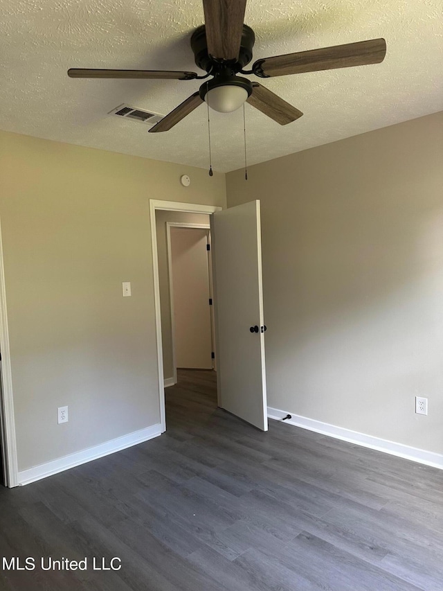 unfurnished room featuring a textured ceiling, baseboards, visible vents, ceiling fan, and dark wood-type flooring