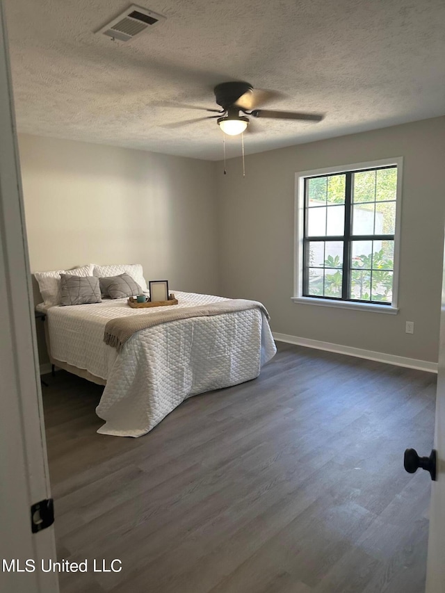 bedroom featuring dark wood-type flooring, ceiling fan, and a textured ceiling