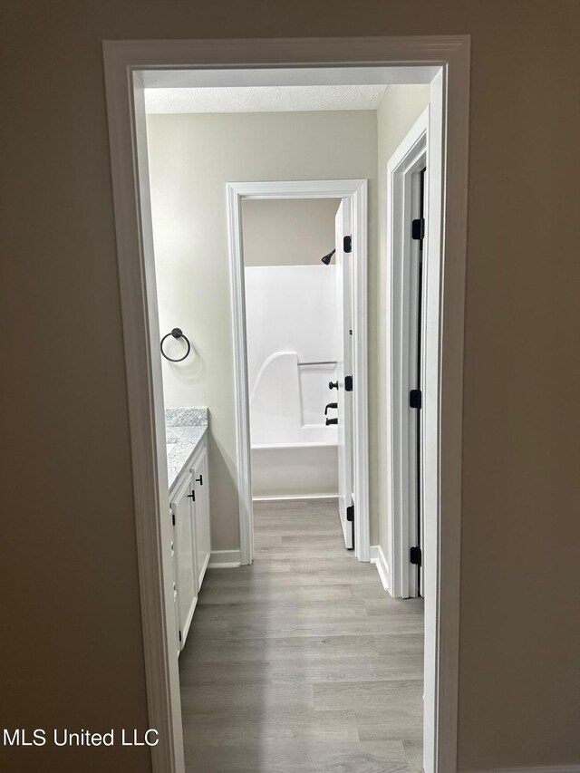 full bathroom with baseboards, wood finished floors, vanity, and shower / washtub combination