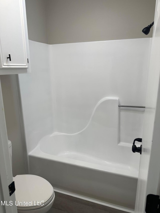 bathroom with toilet, wood-type flooring, and tub / shower combination