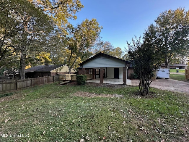 rear view of property featuring a lawn, a wooden deck, fence, and brick siding