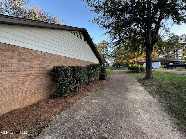 view of side of home with brick siding and a yard