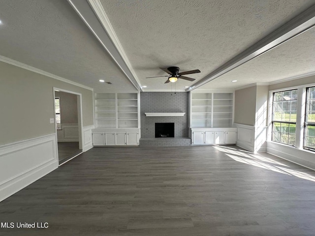 unfurnished living room with a textured ceiling, built in shelves, a ceiling fan, a fireplace, and ornamental molding