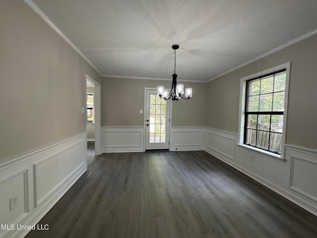 unfurnished dining area with plenty of natural light, a wainscoted wall, a notable chandelier, and dark wood-style flooring