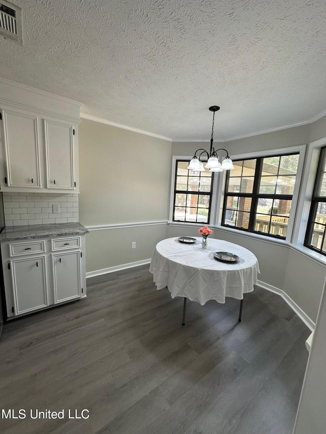 dining area featuring ornamental molding, a notable chandelier, dark hardwood / wood-style floors, and a textured ceiling