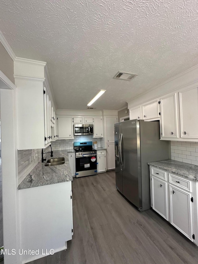 kitchen featuring decorative backsplash, dark wood-type flooring, stainless steel appliances, sink, and white cabinets