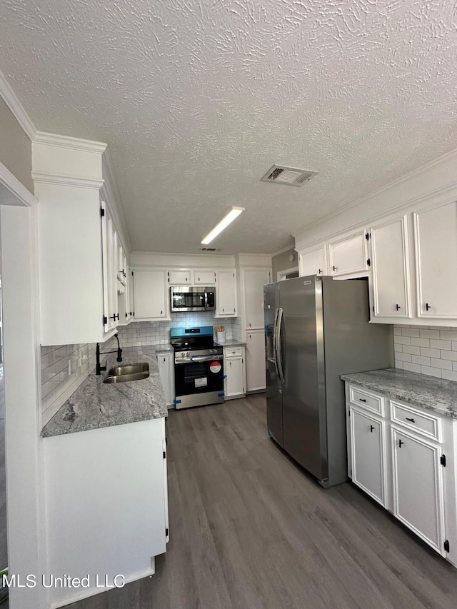 kitchen with a sink, a textured ceiling, tasteful backsplash, white cabinetry, and appliances with stainless steel finishes