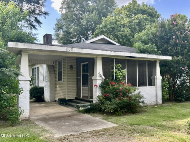 2305 Grenada Blvd, Greenwood, MS 38930 - view of front facade featuring a chimney, brick siding, a front lawn, driveway, and an attached carport