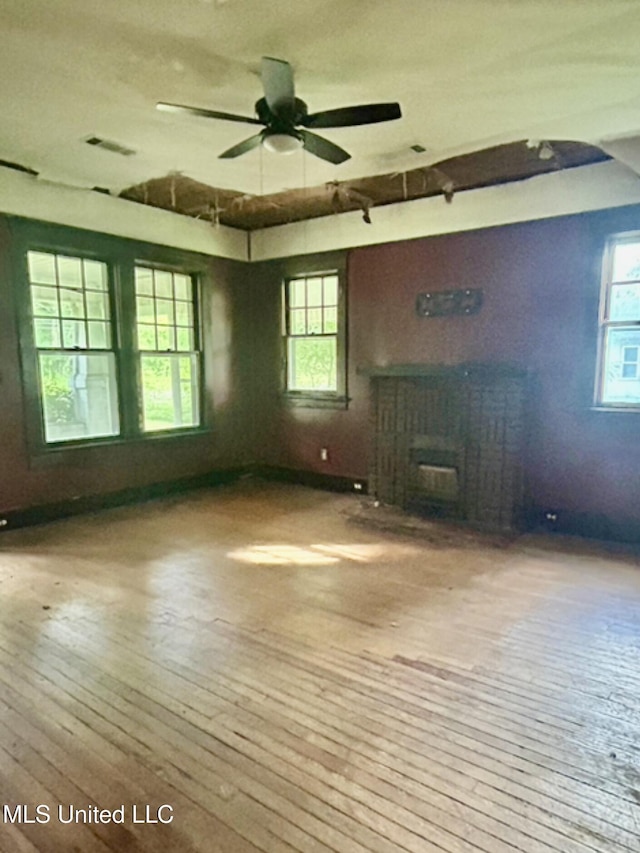 2305 Grenada Blvd, Greenwood, MS 38930 - unfurnished living room featuring a fireplace, hardwood / wood-style floors, and a ceiling fan