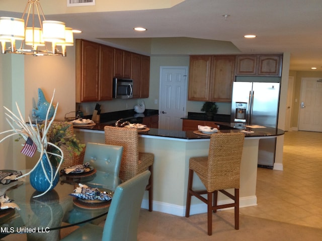 kitchen with kitchen peninsula, a kitchen bar, pendant lighting, and appliances with stainless steel finishes