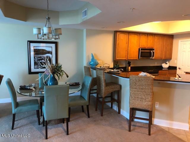 kitchen featuring a breakfast bar area, a chandelier, pendant lighting, and light colored carpet