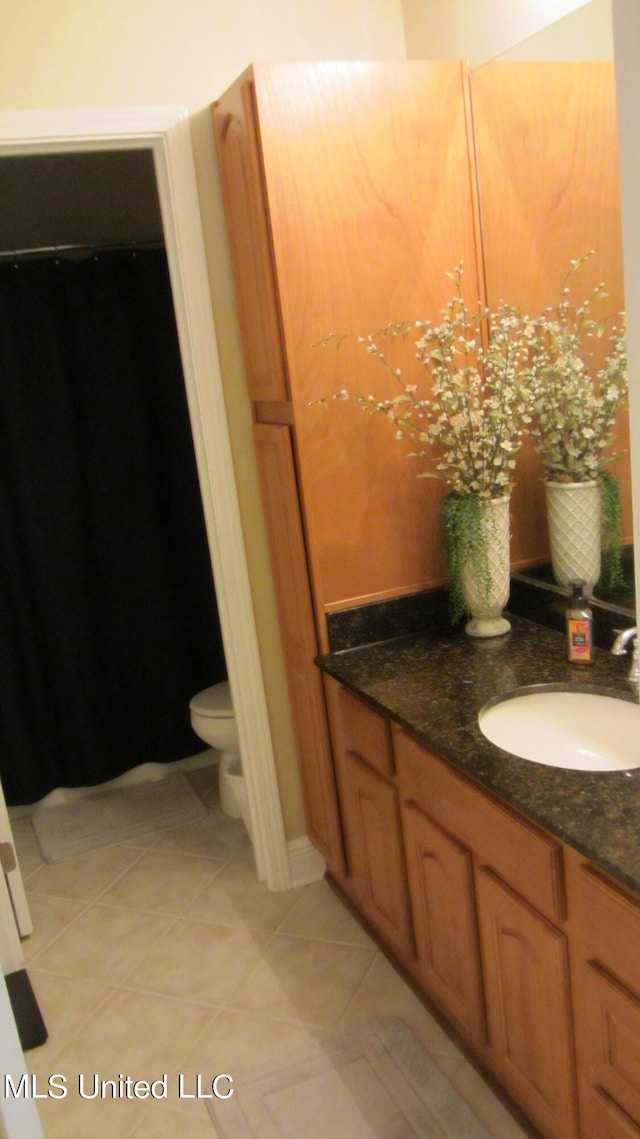 bathroom with toilet, vanity, and tile patterned flooring