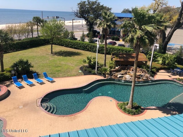 view of swimming pool featuring a yard and a water view