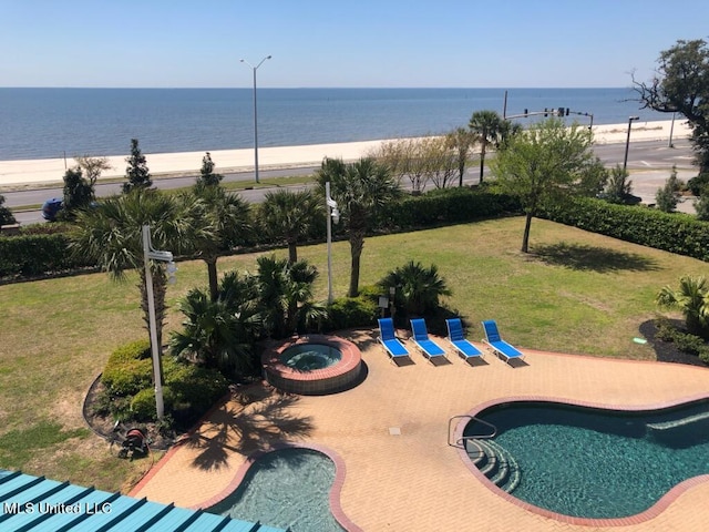 view of swimming pool with a community hot tub, a beach view, a patio, a yard, and a water view