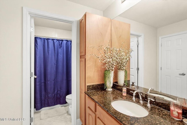 bathroom with toilet, vanity, and tile patterned floors