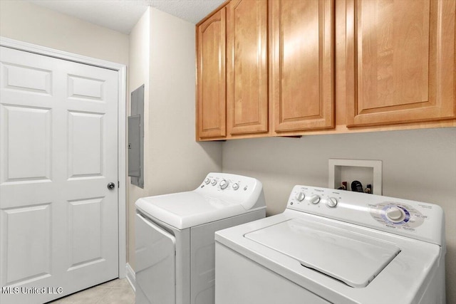 washroom featuring washing machine and dryer, cabinets, electric panel, and light tile patterned flooring