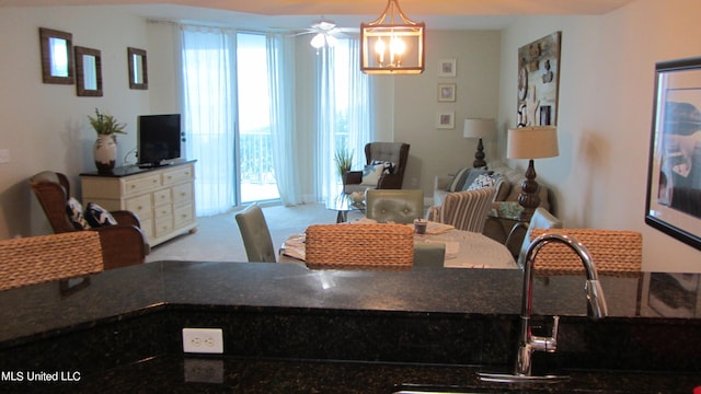 carpeted dining space featuring sink and ceiling fan with notable chandelier