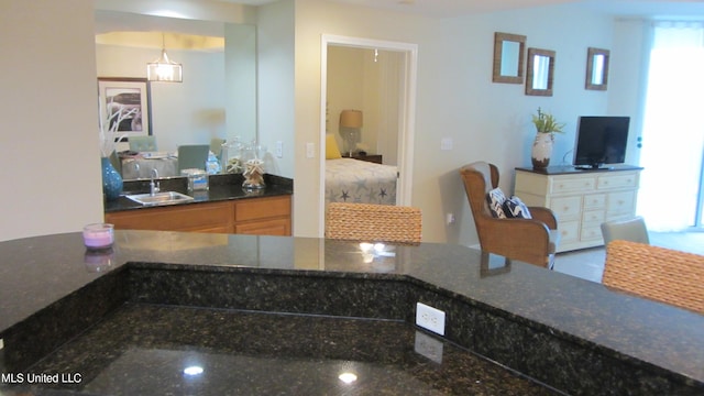 kitchen with dark stone counters, hanging light fixtures, and sink