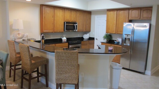 kitchen with a kitchen bar, kitchen peninsula, stainless steel appliances, and sink